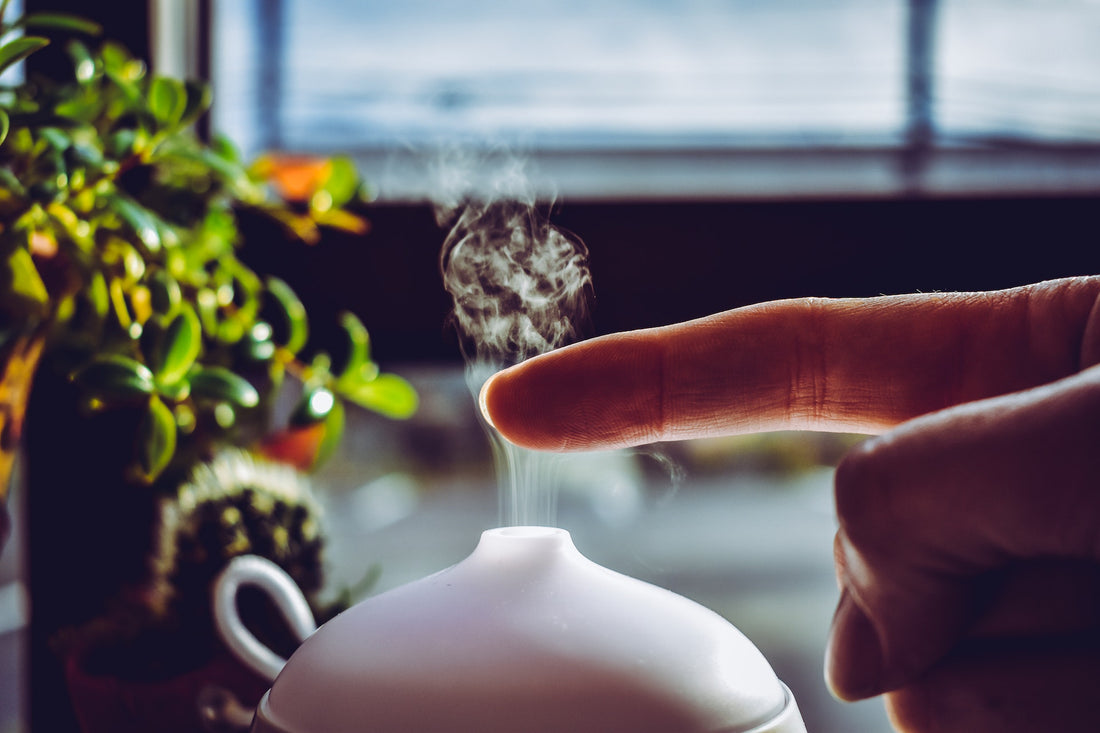 Person with finger over essential oils being diffused